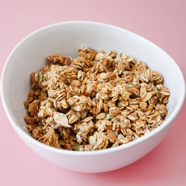 Cereal con flake whole grains in white bowl on pink background. - Фото, изображение