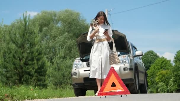 Business nainen odottaa apua lähellä hänen autonsa rikki tien puolella, joilla on ongelmia hänen rikki auto, hätäpalvelu tiellä - Materiaali, video