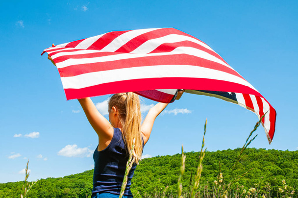 Young woman holding American flag on blue sky background.  - Fotó, kép
