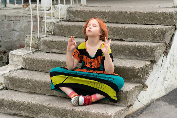 little girl sitting on the stairs in a colored dress - Foto, Imagen
