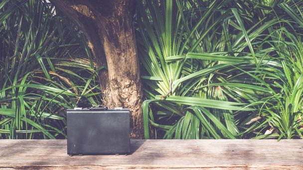 Black business leather briefcase on wooden surface with green nature background - Foto, afbeelding
