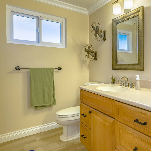 Doble tocador cuadrado con armarios de madera dentro de un baño con ventana pequeña
 - Foto, imagen