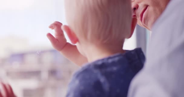 Close up shot of father holding baby daughter looking out window smiling and laughing  - Materiał filmowy, wideo