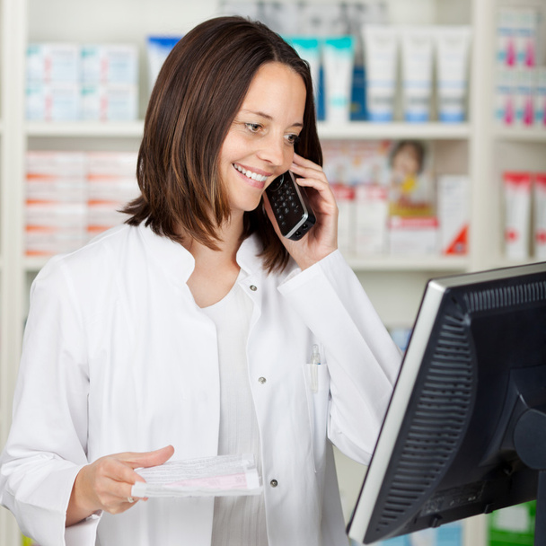 Pharmacist Using Cordless Phone While Looking At Computer - Foto, Imagem