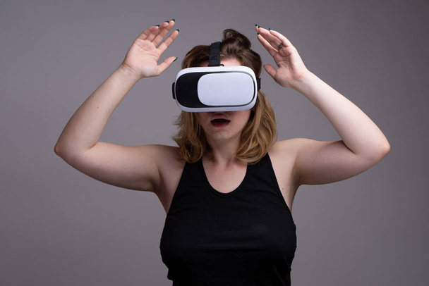 Η γυναίκα που χρησιμοποιεί VR εργαλείο κρατά τα χέρια της ψηλά ως εμφάνιση σοκαρισμένοι εκφράσεων - Φωτογραφία, εικόνα