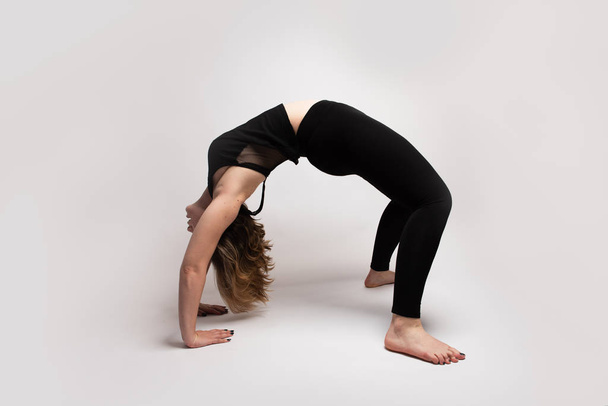Mulher loira isolada flexível fazendo uma ponte na aula de ioga
 - Foto, Imagem
