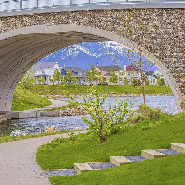 Frame Square Arched bridge over a glistening lake with a view of homes and snowy mountain - Photo, Image