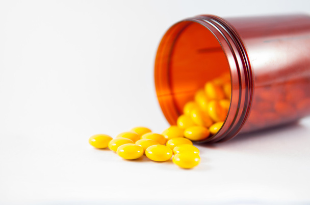 Keltainen päällystetty tabletti ja ruskea reseptipurkki
 - Valokuva, kuva