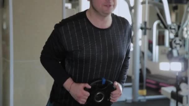 Egy túlsúlyos felnőtt ember végez túlnyúlását egy tornaterem. - Felvétel, videó