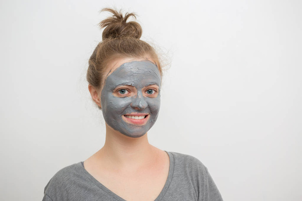 Young caucasian woman with black or grey facial clay mask on her face, smiling - Photo, Image