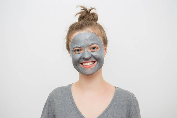 Młoda kaukaski kobieta z czarnym lub szarym twarzy maska gliny na jej twarzy, uśmiechnięty - Zdjęcie, obraz