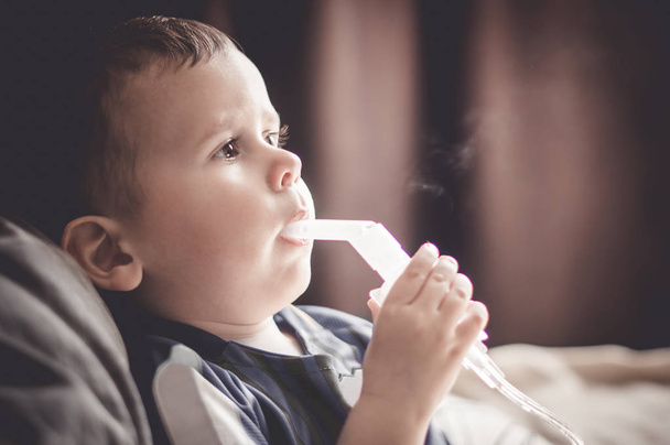 Two year old boy making inhalation with nebulizer at home. - Foto, imagen