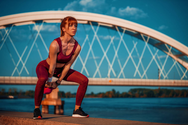 Portrait of fitness woman workout with kettlebell in the city. - Fotografie, Obrázek
