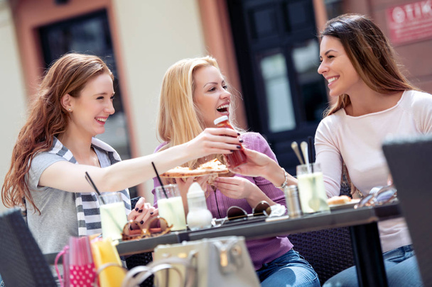 Amis féminins manger de la pizza dans le café.Les gens, la nourriture, le plaisir et le bonheur concept
. - Photo, image