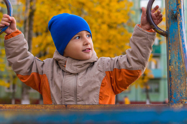 jongen spelen op de speelplaats in de herfst - Foto, afbeelding