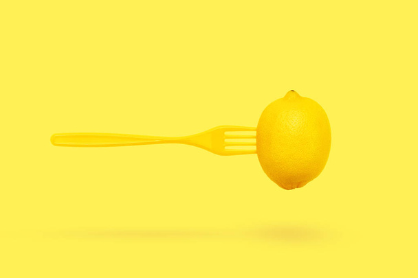 Zitrone und Gabel schweben auf pastellgelbem Hintergrund minimales Sommerkonzept. - Foto, Bild
