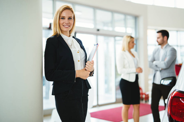 Picture of professional female salesperson working in car dealership - Fotó, kép