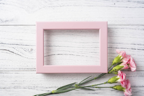 Top view of pink carnations flowers with photo frame on white vintage wooden background for mother day mockup - Фото, зображення