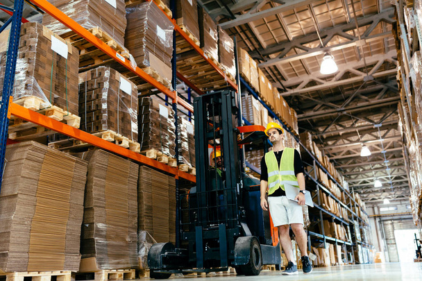Warehouse industry worker doing logistics work with forklift loader - 写真・画像