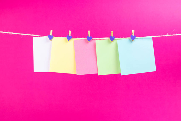 Colorful paper cards hanging rope isolated on hot pink background. Place for your text. - Foto, Imagem