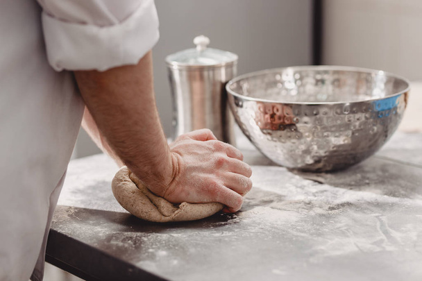 Baker punchs down the dough in the kitchen in the bakery - Foto, imagen