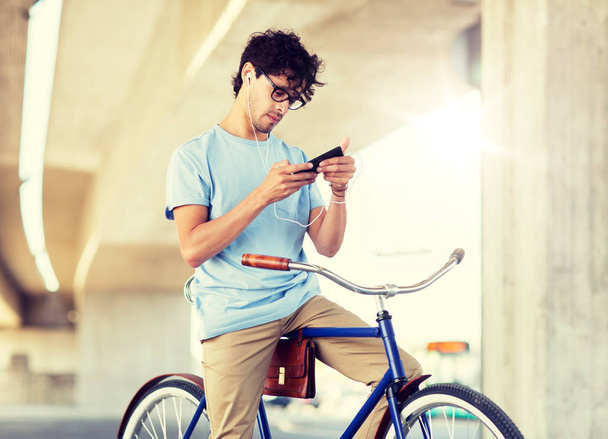 man with smartphone and earphones on bicycle - Foto, Bild