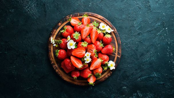 Fresh strawberries in a plate on a black stone background. Berries Top view. Free space for your text. - Foto, immagini