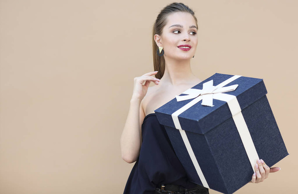 Cute girl in navy blue clothes holding big gift box - Φωτογραφία, εικόνα