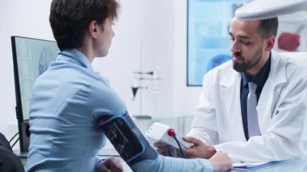 Kaukasischer Arzt misst Blutdruck mit digitalem Blutdruckmessgerät - Filmmaterial, Video
