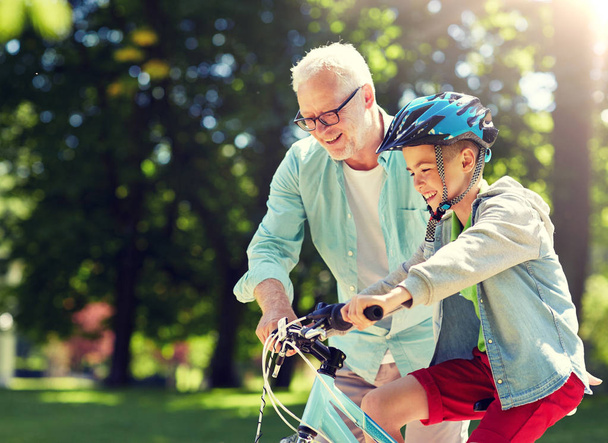 grandfather and boy with bicycle at summer park - Photo, Image