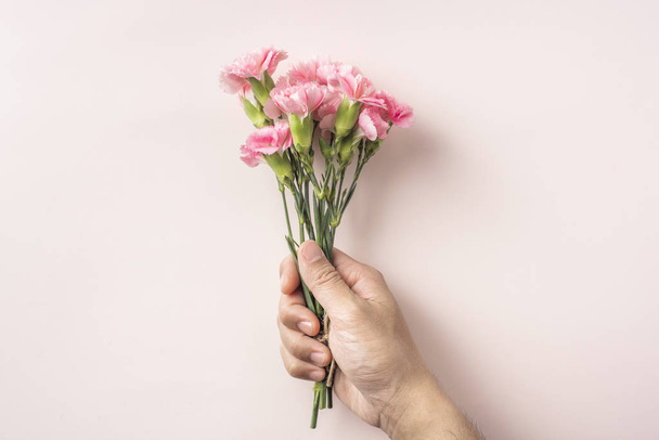 Top view bunch of carnations flowers in male hand on pink background - Φωτογραφία, εικόνα