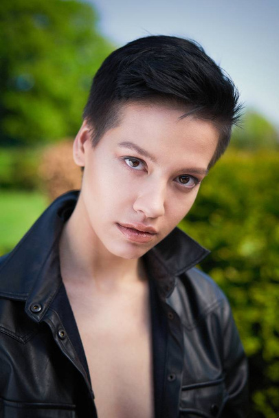 Young woman in black leather shirt posing in summer park - Zdjęcie, obraz
