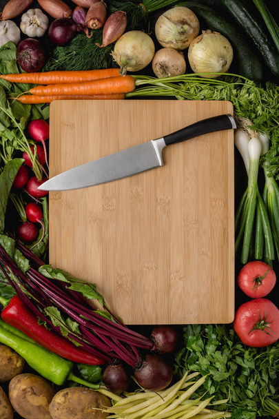 Coltello da cucina su tagliere in legno con verdure fresche. Cibo crudo vegano. Concetto di alimentazione sana
. - Foto, immagini