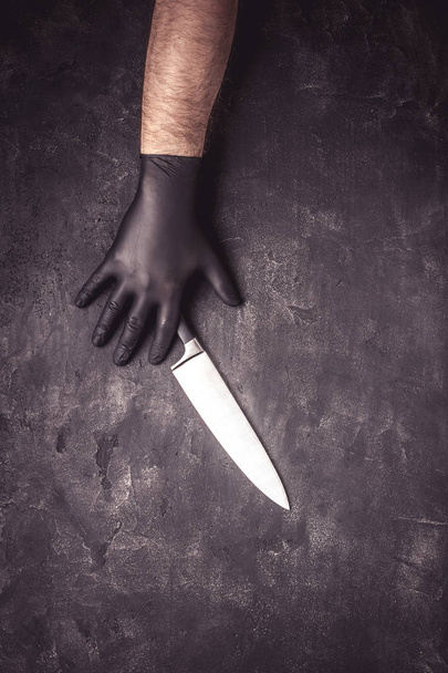 Manos masculinas con guantes de látex negro y cuchillo sobre fondo oscuro
 - Foto, Imagen