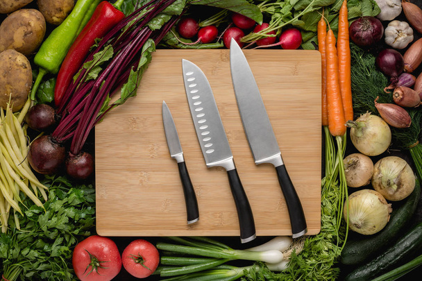 Ensemble de couteaux de cuisine avec légumes frais sur planche à découper en bois. Nourriture crue végétarienne. Concept de saine alimentation
. - Photo, image