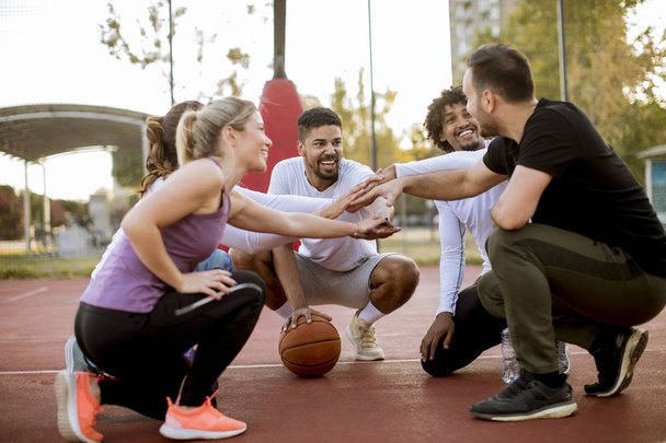 Groupe multiethnique de jeunes joueurs de basket-ball reposant ensemble sur le court
 - Photo, image