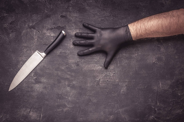 Manos masculinas con guantes de látex negro y cuchillo sobre fondo oscuro
 - Foto, Imagen