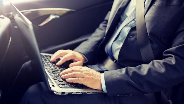 senior businessman with laptop driving in car - Photo, image