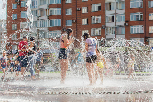 Novokuznetsk, Kemerovo Region, Russia - August 04, 2018: Happy children splashing in a water of a city fountain and enjoying the cool streams of water in a hot day. - Photo, image