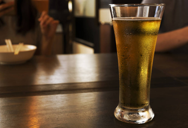 Zimne piwo w wysokiej szklance na drewnianym stole - Zdjęcie, obraz