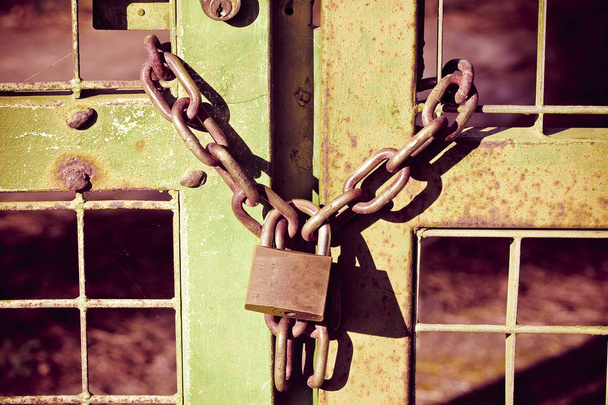 Puerta metálica oxidada verde cerrada con cadena y candado - concepto i
 - Foto, Imagen