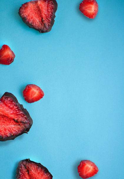Strawberries in a plate with chocolate on a blue background - Photo, Image