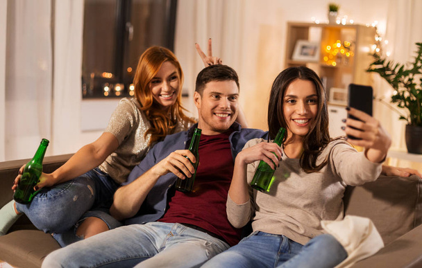 friends clinking drinks and taking selfie at home - Foto, afbeelding