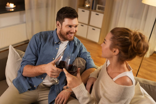 happy couple drinking red wine at home in evening - Φωτογραφία, εικόνα