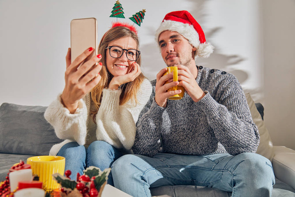 Ευτυχισμένο ζευγάρι απολαμβάνοντας την Πρωτοχρονιά/παραμονή Χριστουγέννων με κινητό τηλέφωνο  - Φωτογραφία, εικόνα