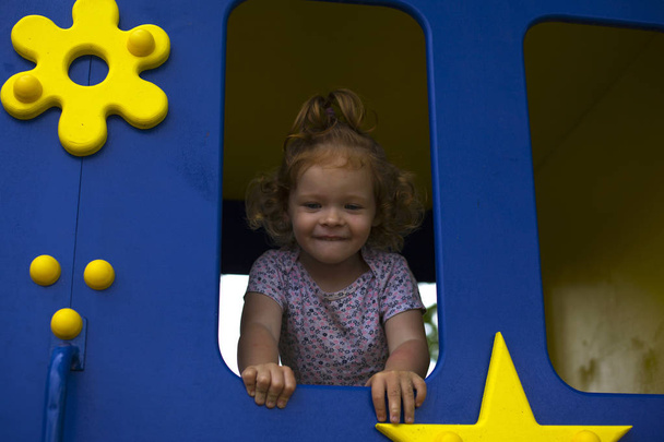 redhead little  girl in a wooden house for children on the playground - Photo, Image