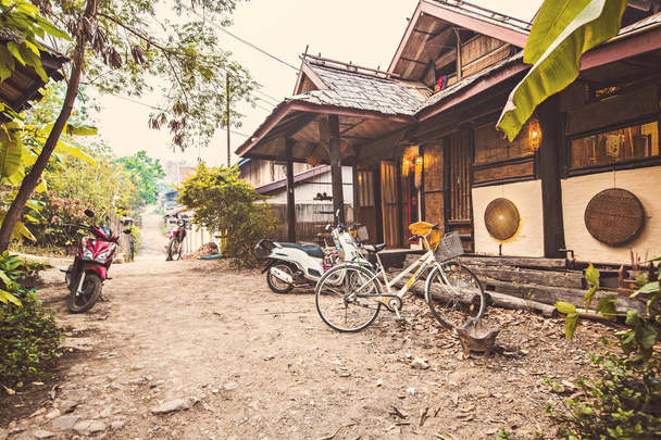 LUANG PRABANG, LAOS - March 2019: Traditional Lao style villa in tropical garden with bicycle parked next to it in Luang Prabang, Laos - Foto, imagen