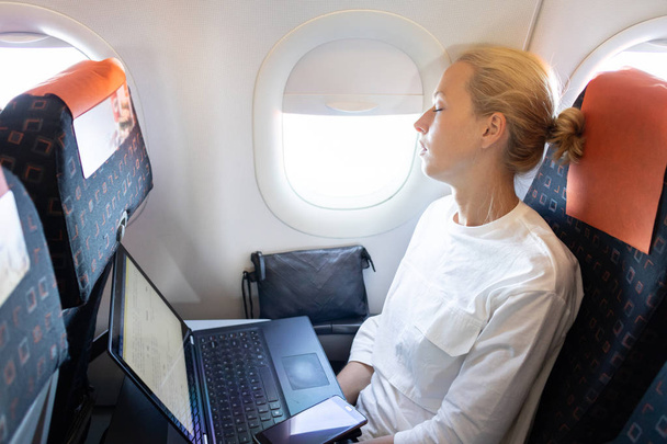 Уставшая деловая женщина, дремлющая в самолете во время своей деловой поездки по делам
. - Фото, изображение