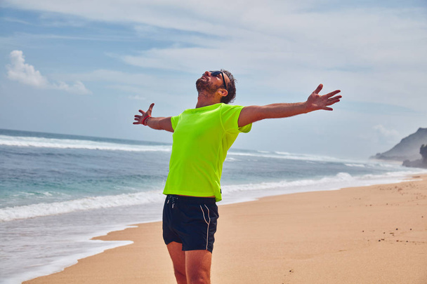 Man celebrating success after good training / exercise on a sand - Foto, imagen