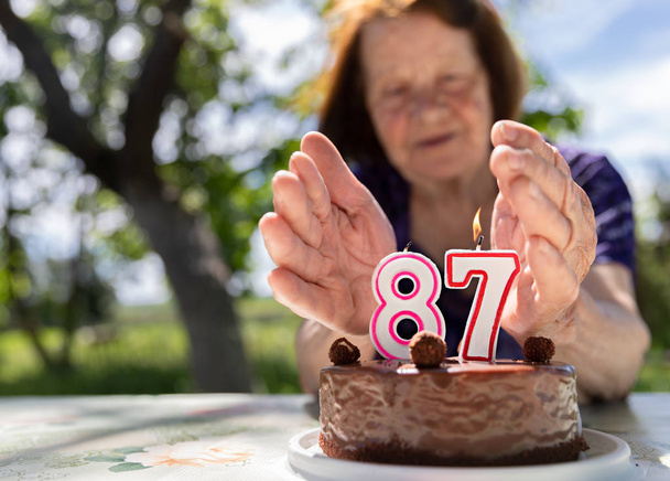 Η ηλικιωμένη γυναίκα είναι λυπημένη με την γιορτινή τούρτα. Γεράματα. Αντιγραφή χώρου - Φωτογραφία, εικόνα